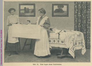 Dienstmädchen beim Falten von Tischwäsche